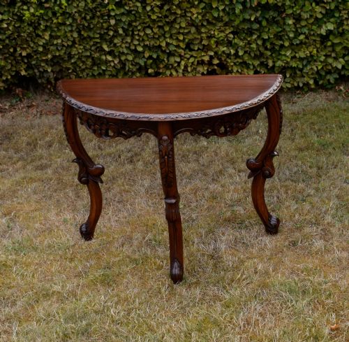 fig 5. A dark mahogany demi-lune console table featuring deep acanthus leaf carvings on the frieze and three cabriole legs.