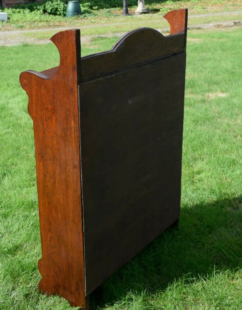 fig 6. An early twentieth-century open oak bookcase featuring a carved floral crest on the top gallery, shaped sides, and three fixed shelves.
