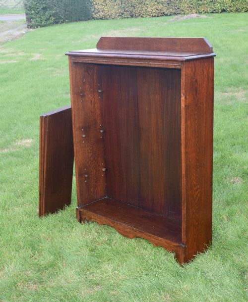 fig 5. An early 20th-century open dark oak bookcase with four shelves, a low top gallery, and a scalloped plinth base.
