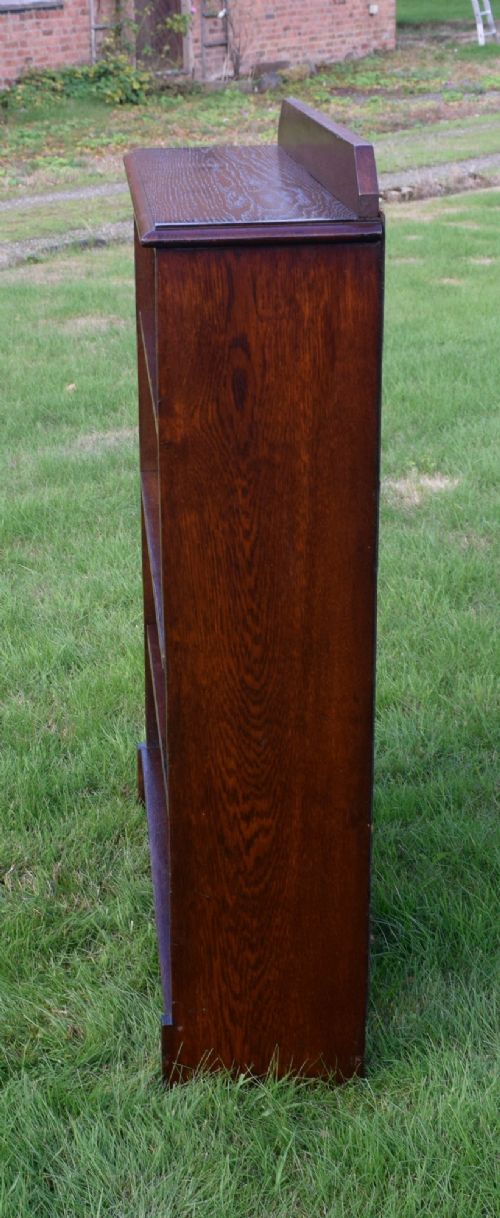 An early 20th-century open dark oak bookcase with four shelves, a low top gallery, and a scalloped plinth base. View IX