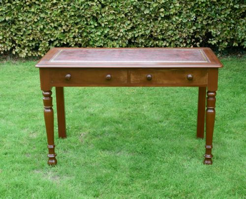 fig 1. A Victorian mahogany writing table with a red leather inset surface, two drawers with wooden knob handles, turned front legs, and square back legs.