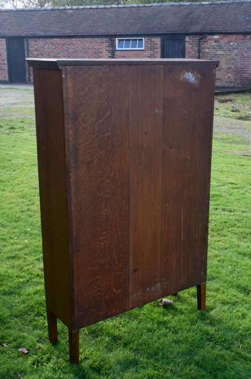 fig 3. An early twentieth-century warm brown oak bookcase featuring twin glazed doors, brass hardware, and three internal shelves.