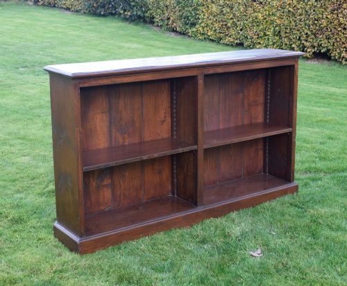 fig 1. A wide early 20th-century low open oak bookcase with two main compartments, a central vertical divider, plank backboard, and a moulded top edge.