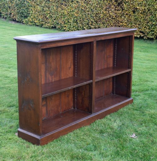 fig 2. A wide early 20th-century low open oak bookcase with two main compartments, a central vertical divider, plank backboard, and a moulded top edge.