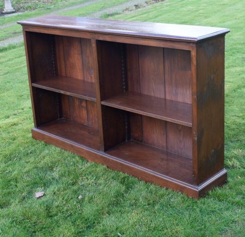 fig 3. A wide early 20th-century low open oak bookcase with two main compartments, a central vertical divider, plank backboard, and a moulded top edge.