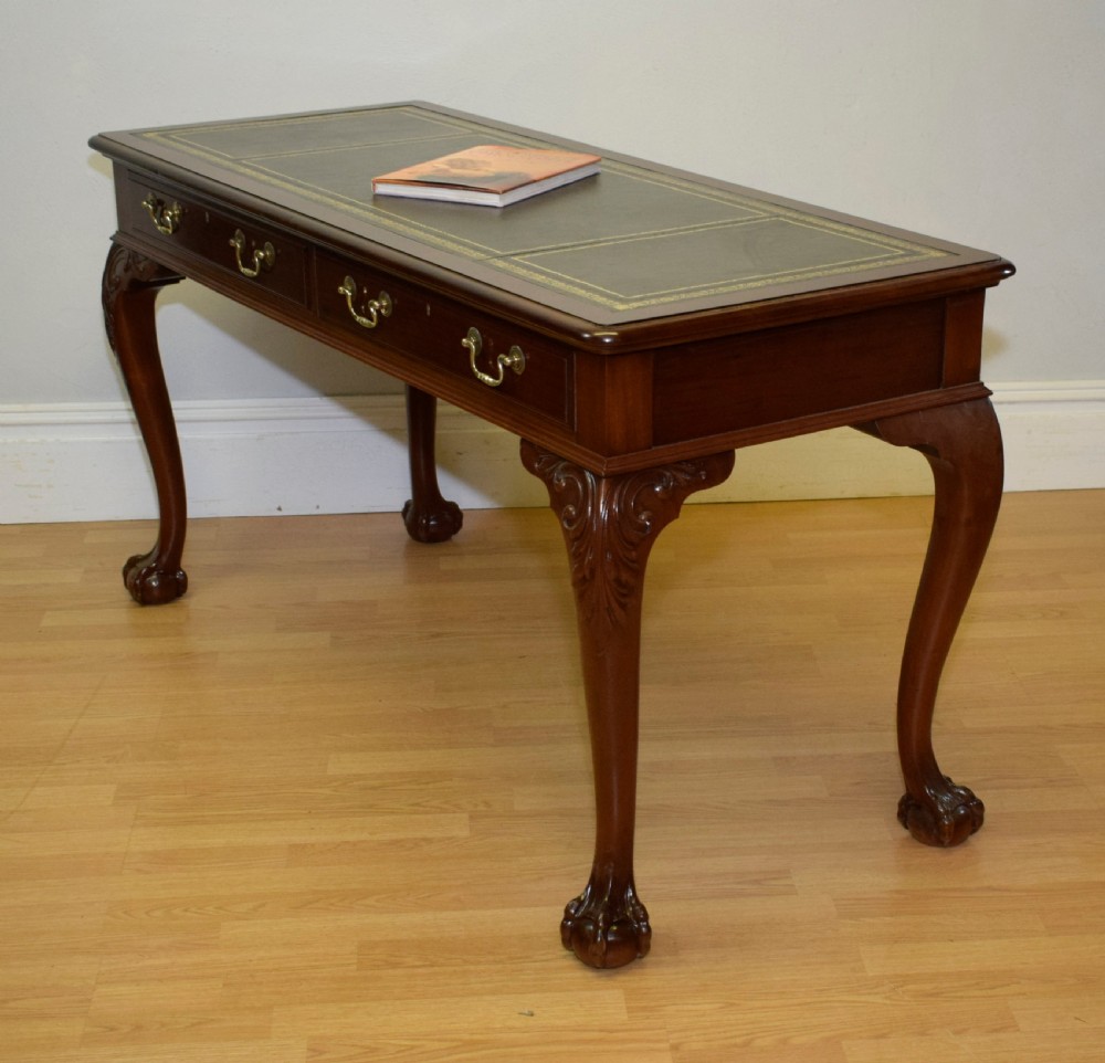 A mahogany library writing table featuring a green leather inset top, brass drop handles, and carved cabriole legs terminating in claw and ball feet. View II