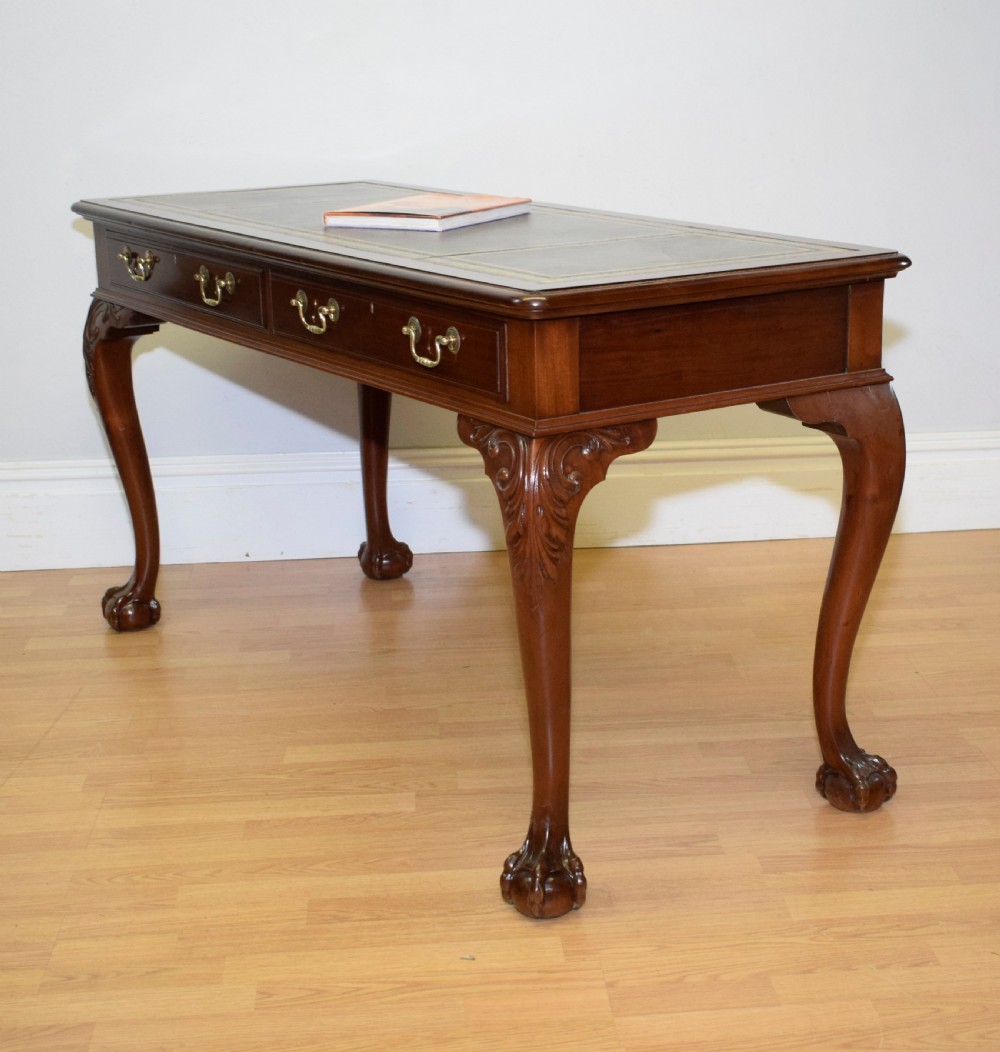 A mahogany library writing table featuring a green leather inset top, brass drop handles, and carved cabriole legs terminating in claw and ball feet. View III