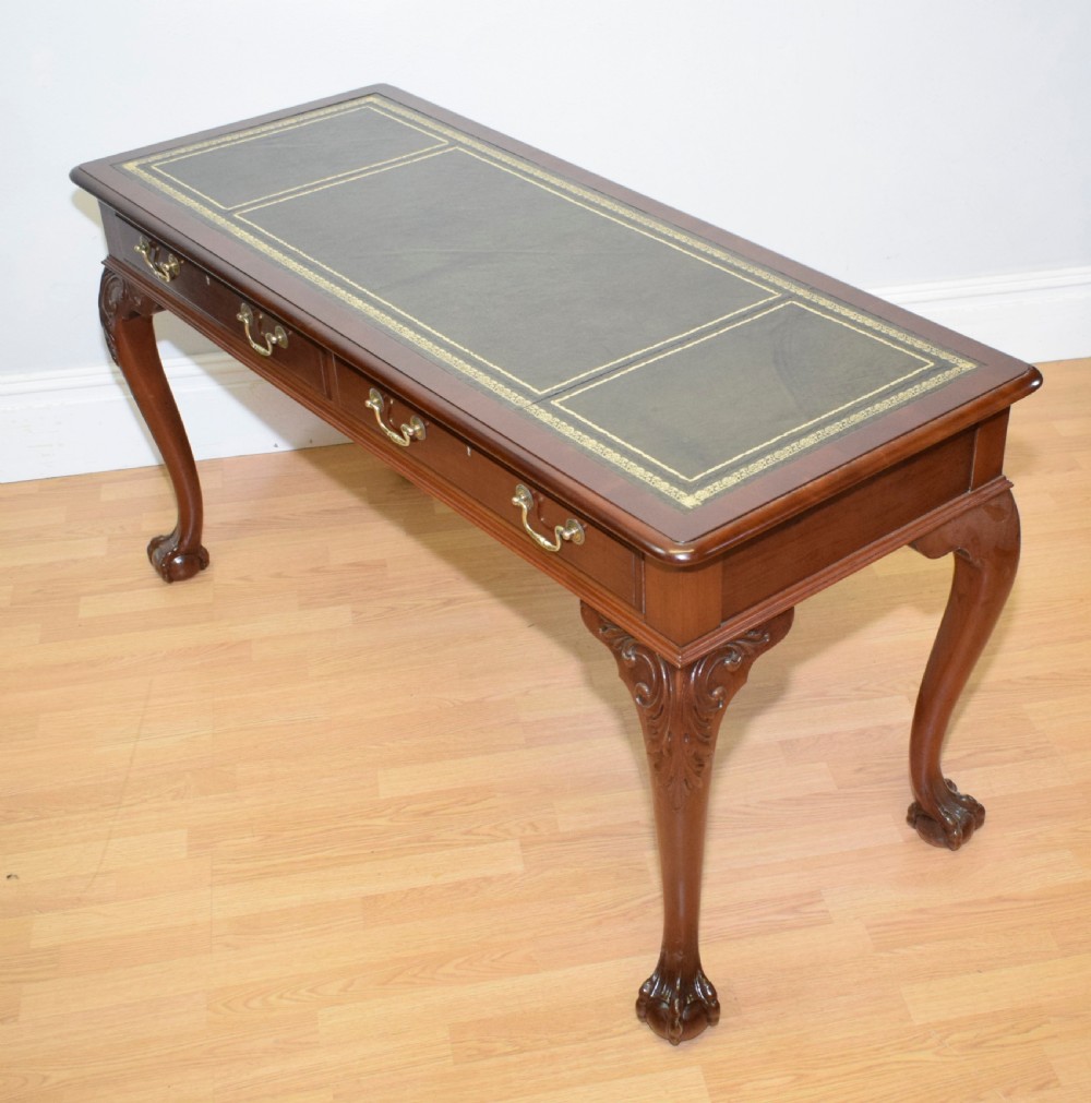 A mahogany library writing table featuring a green leather inset top, brass drop handles, and carved cabriole legs terminating in claw and ball feet. View V