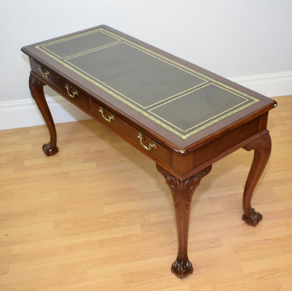 A mahogany library writing table featuring a green leather inset top, brass drop handles, and carved cabriole legs terminating in claw and ball feet. View VI