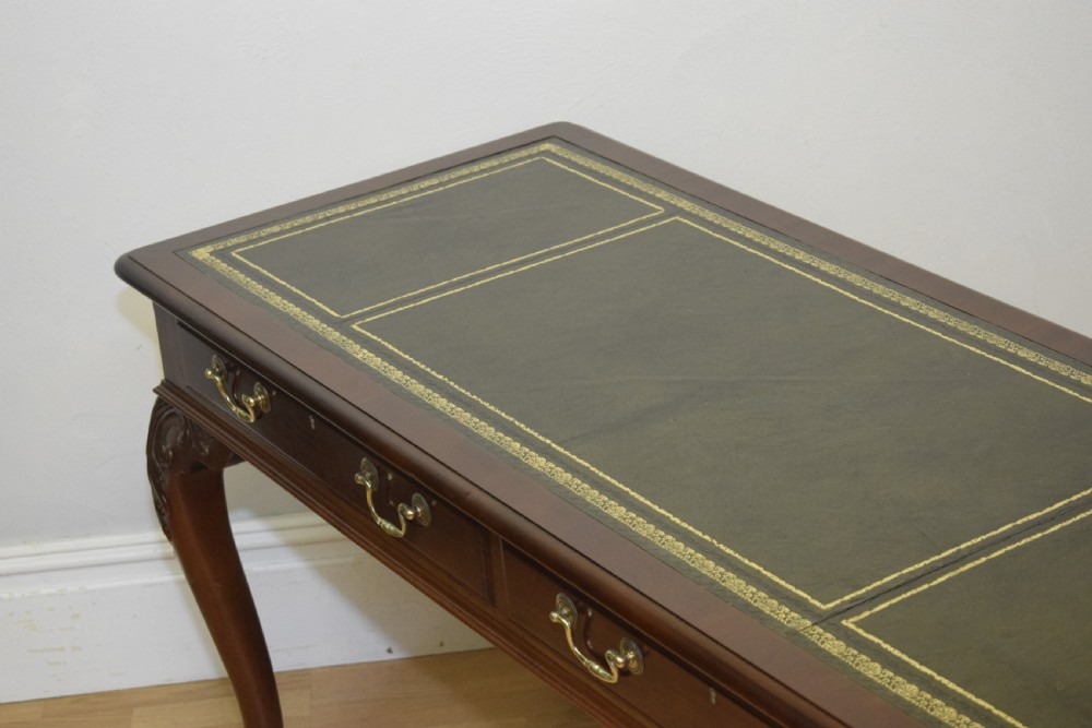 A mahogany library writing table featuring a green leather inset top, brass drop handles, and carved cabriole legs terminating in claw and ball feet. View VII