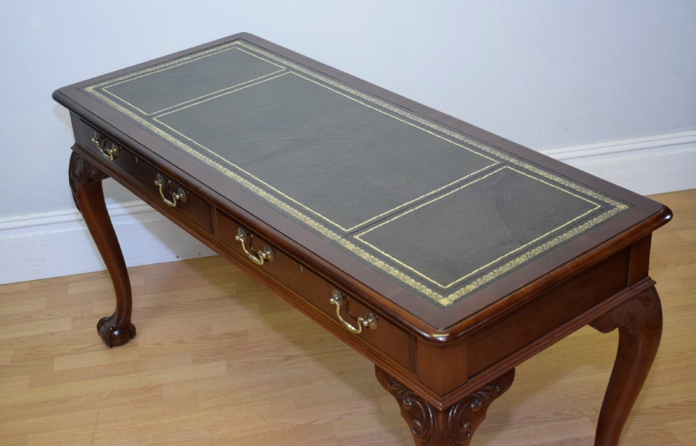 A mahogany library writing table featuring a green leather inset top, brass drop handles, and carved cabriole legs terminating in claw and ball feet. View VIII