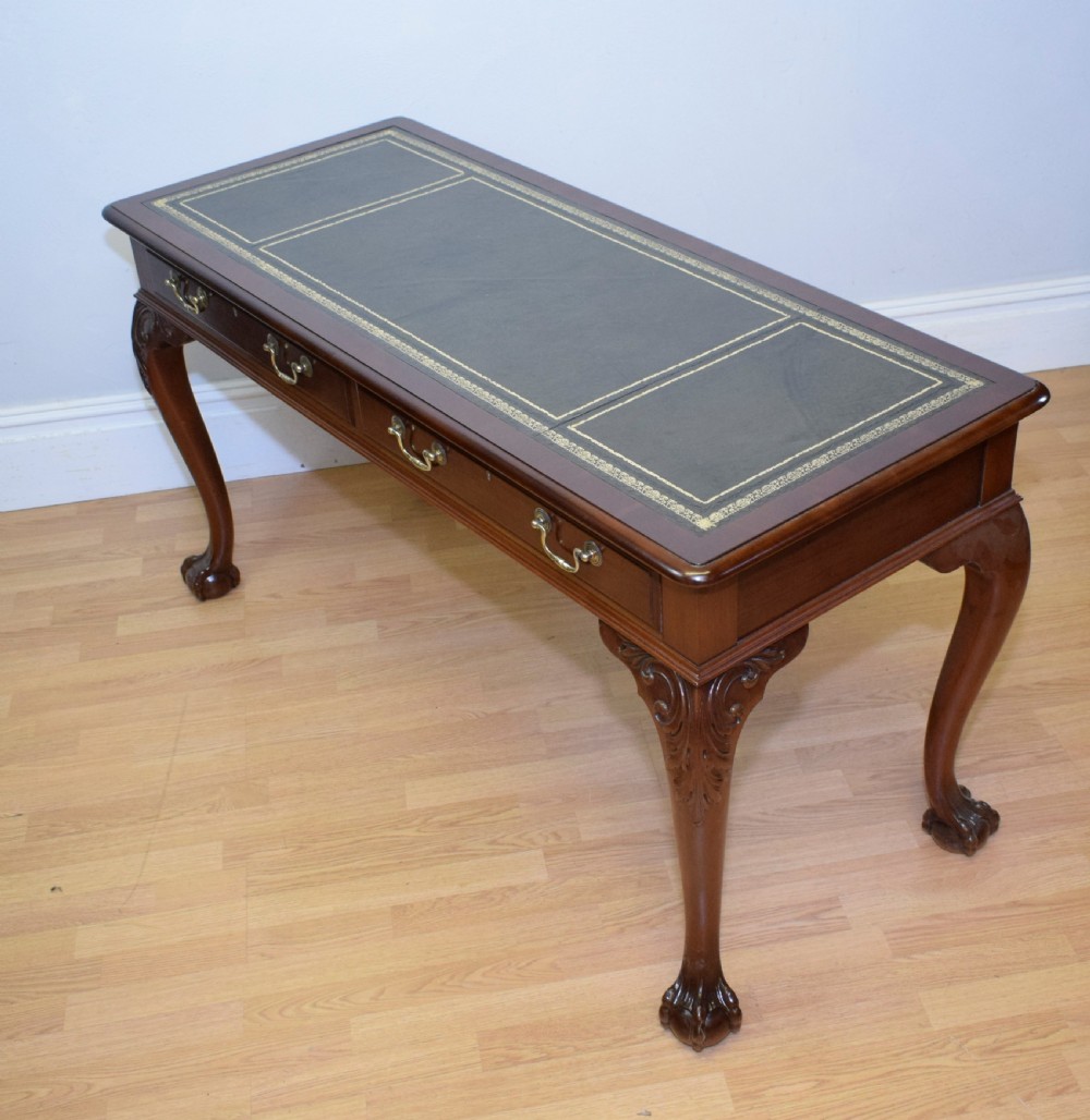 A mahogany library writing table featuring a green leather inset top, brass drop handles, and carved cabriole legs terminating in claw and ball feet. View IX