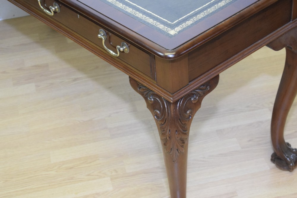 A mahogany library writing table featuring a green leather inset top, brass drop handles, and carved cabriole legs terminating in claw and ball feet. View X