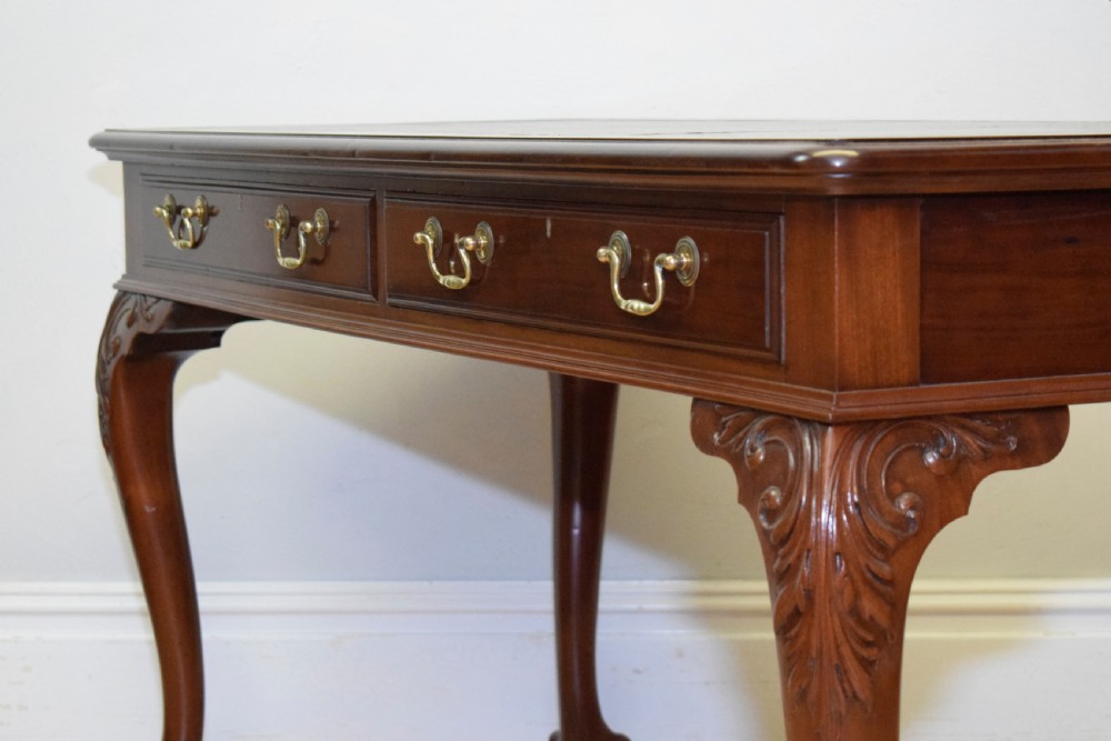 A mahogany library writing table featuring a green leather inset top, brass drop handles, and carved cabriole legs terminating in claw and ball feet. View XI