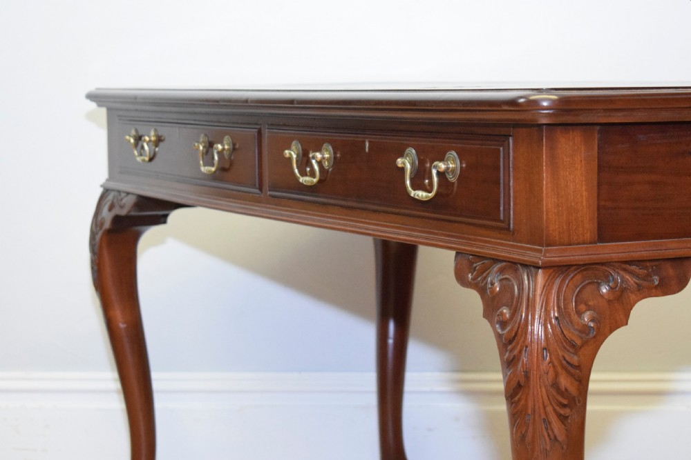 A mahogany library writing table featuring a green leather inset top, brass drop handles, and carved cabriole legs terminating in claw and ball feet. View XII