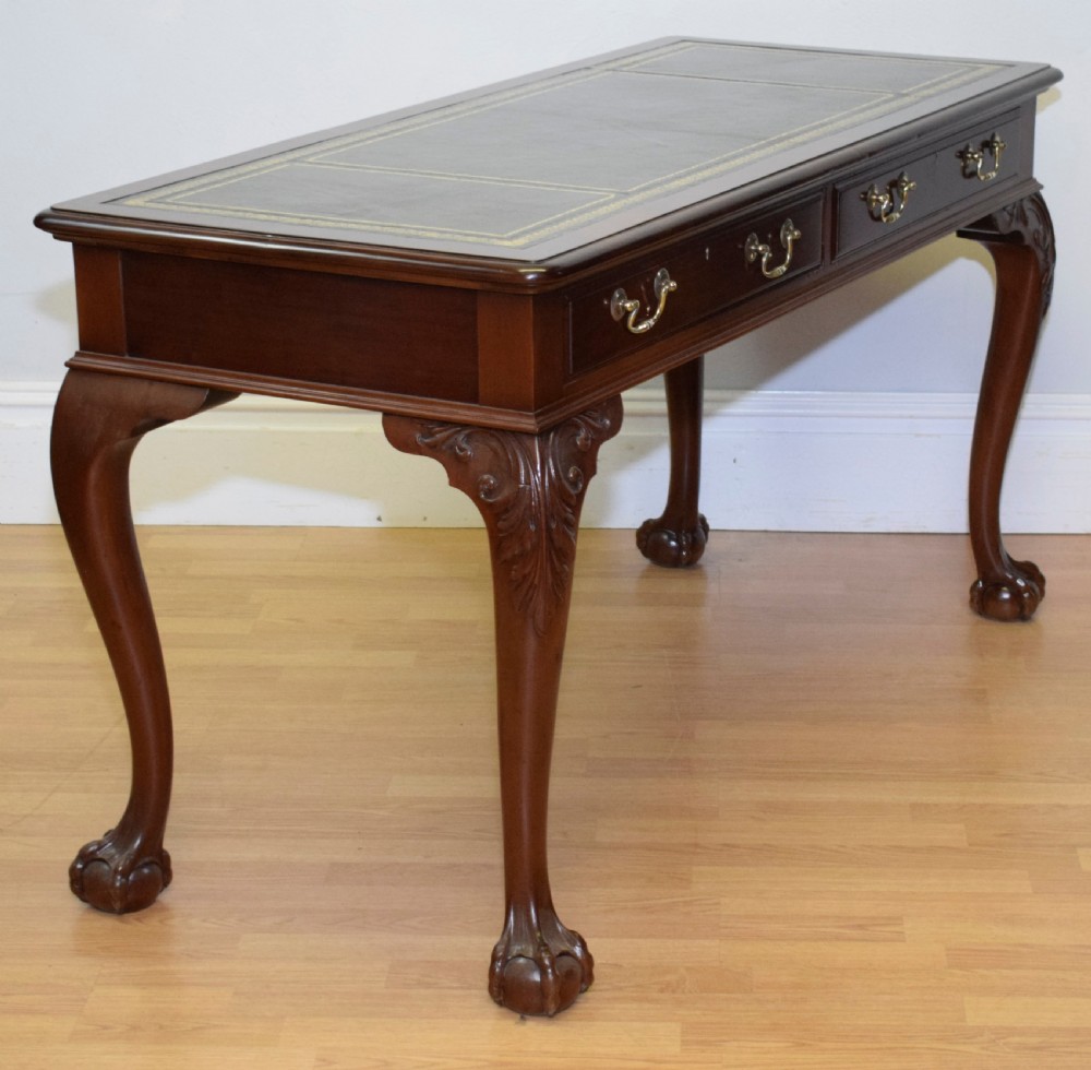 A mahogany library writing table featuring a green leather inset top, brass drop handles, and carved cabriole legs terminating in claw and ball feet. View XV