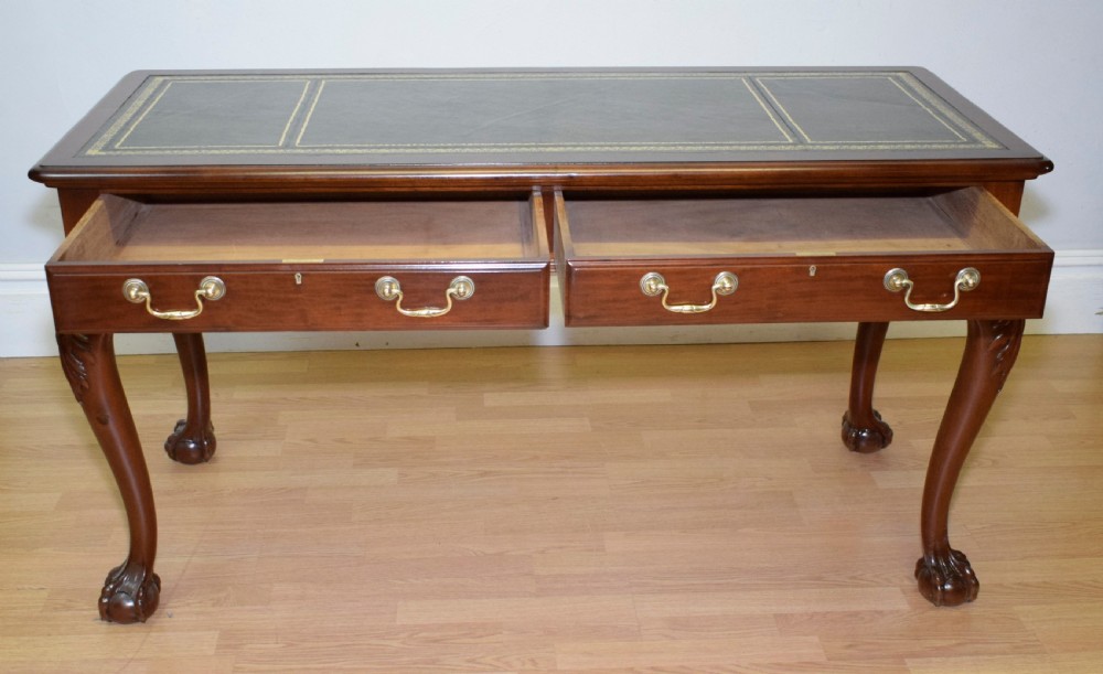 A mahogany library writing table featuring a green leather inset top, brass drop handles, and carved cabriole legs terminating in claw and ball feet. View XX