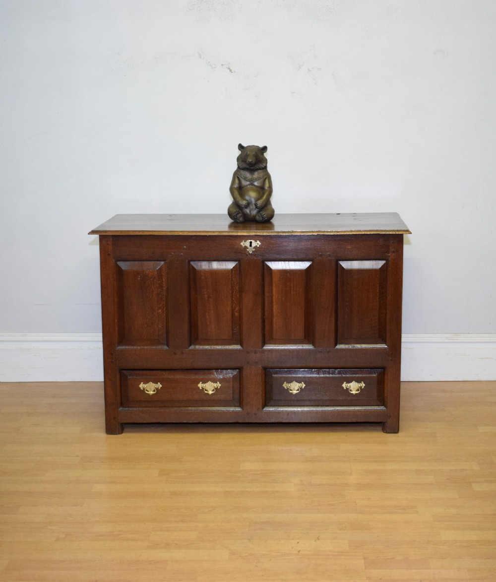 A dark Georgian oak mule chest featuring four fielded front panels and two lower drawers with brass swan-neck handles. View II