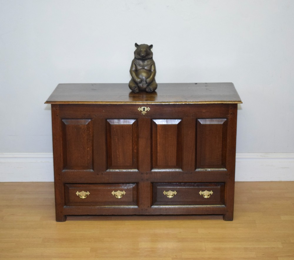 A dark Georgian oak mule chest featuring four fielded front panels and two lower drawers with brass swan-neck handles. View V
