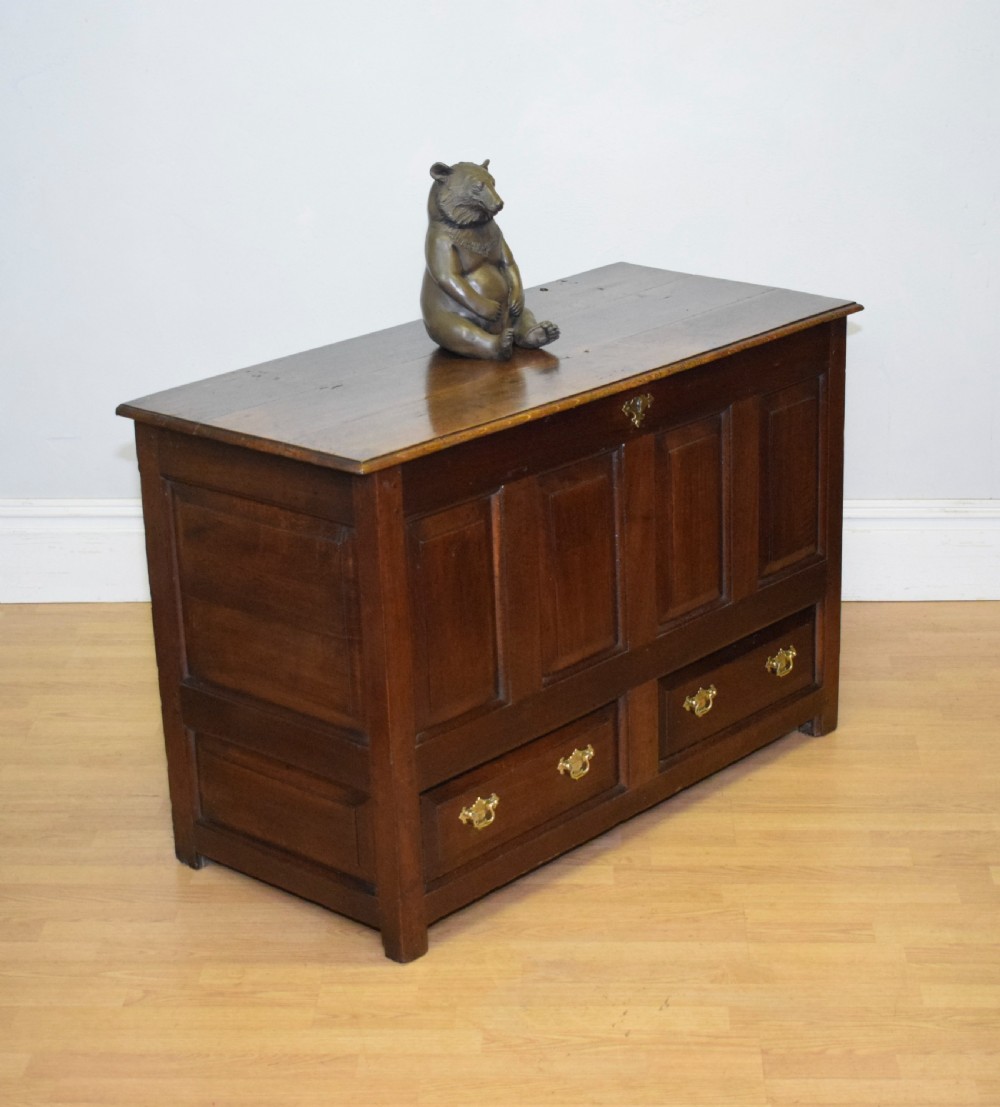 A dark Georgian oak mule chest featuring four fielded front panels and two lower drawers with brass swan-neck handles. View X