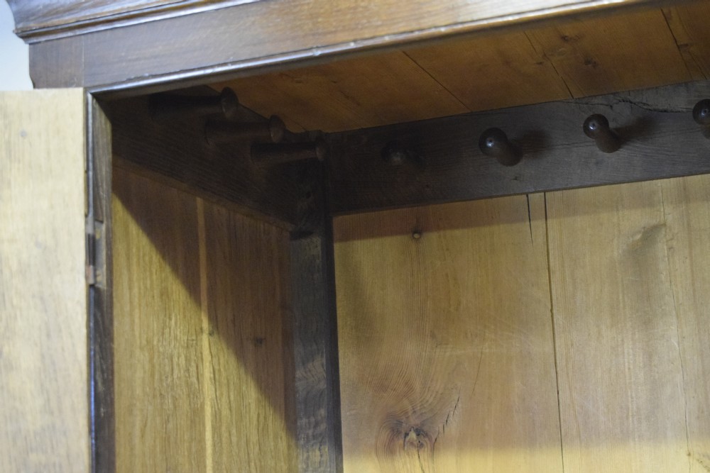 A two-piece Georgian oak press cupboard featuring twin fielded panel doors over a three-drawer base with brass handles. View III