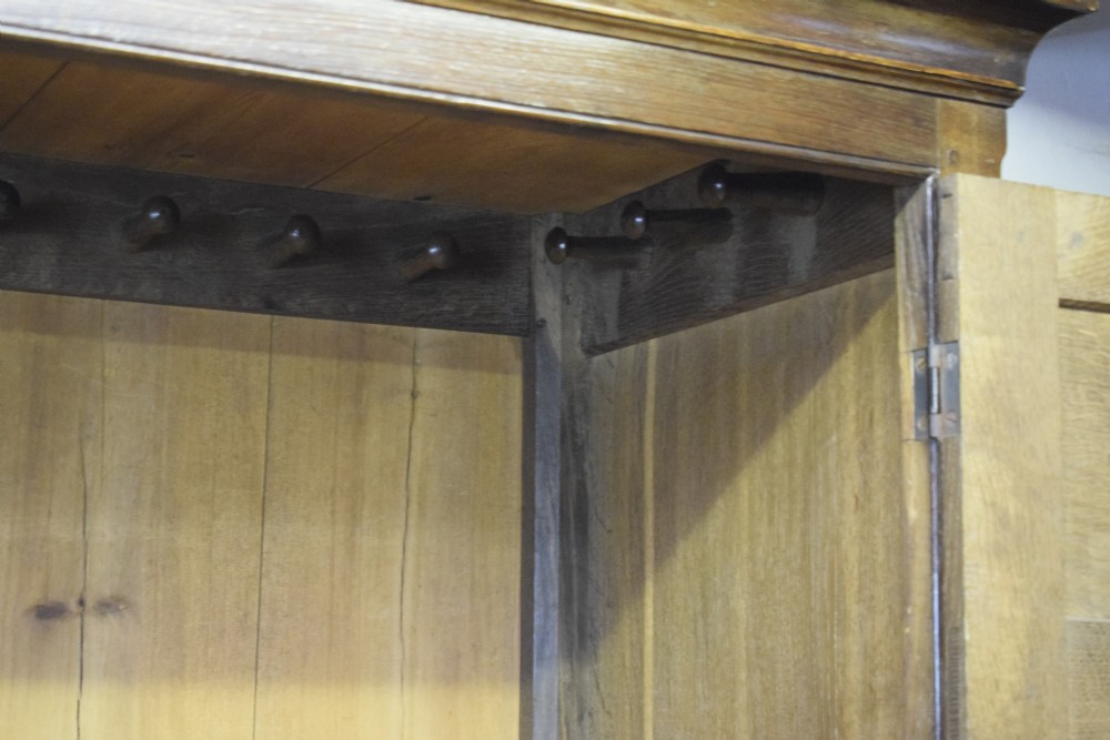 A two-piece Georgian oak press cupboard featuring twin fielded panel doors over a three-drawer base with brass handles. View IV