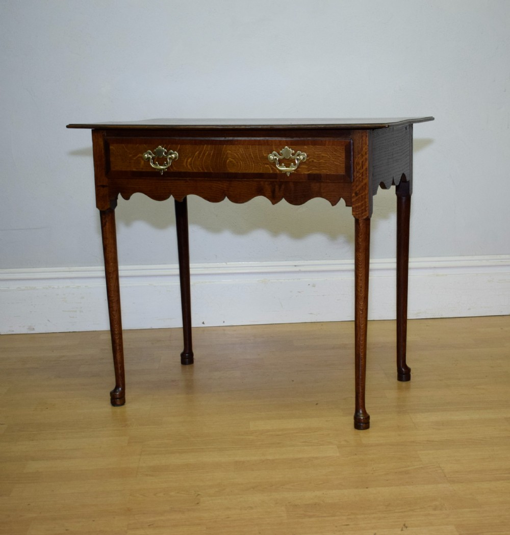 A Georgian oak lowboy side table featuring a single drawer with brass swan-neck handles and a scalloped lower apron. View II