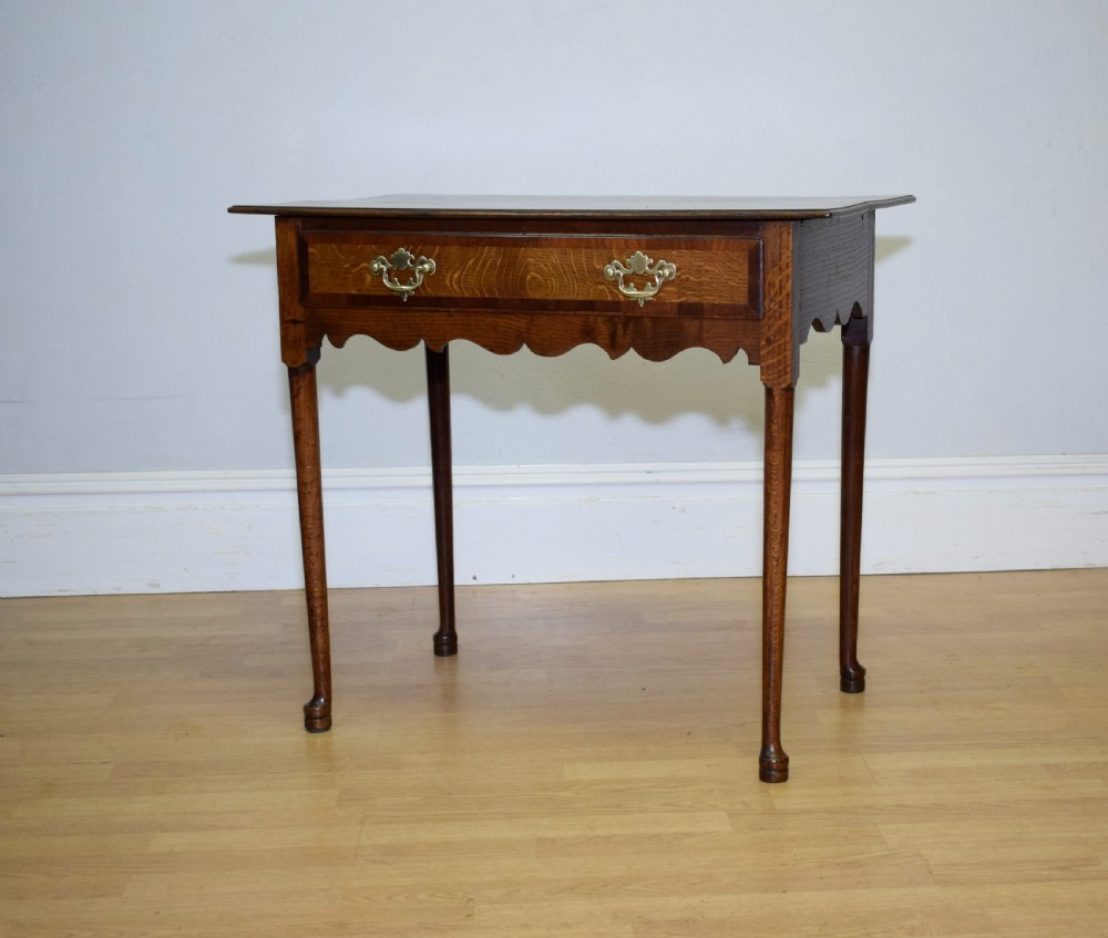 A Georgian oak lowboy side table featuring a single drawer with brass swan-neck handles and a scalloped lower apron. View III