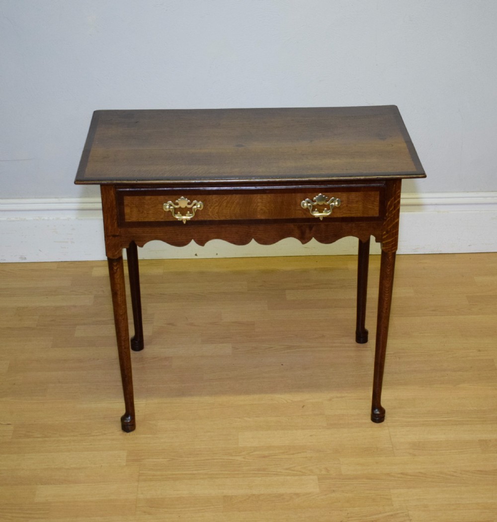 A Georgian oak lowboy side table featuring a single drawer with brass swan-neck handles and a scalloped lower apron. View VII