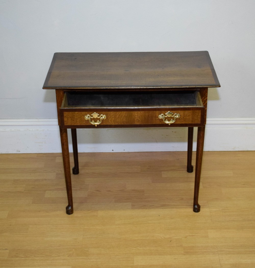 A Georgian oak lowboy side table featuring a single drawer with brass swan-neck handles and a scalloped lower apron. View VIII