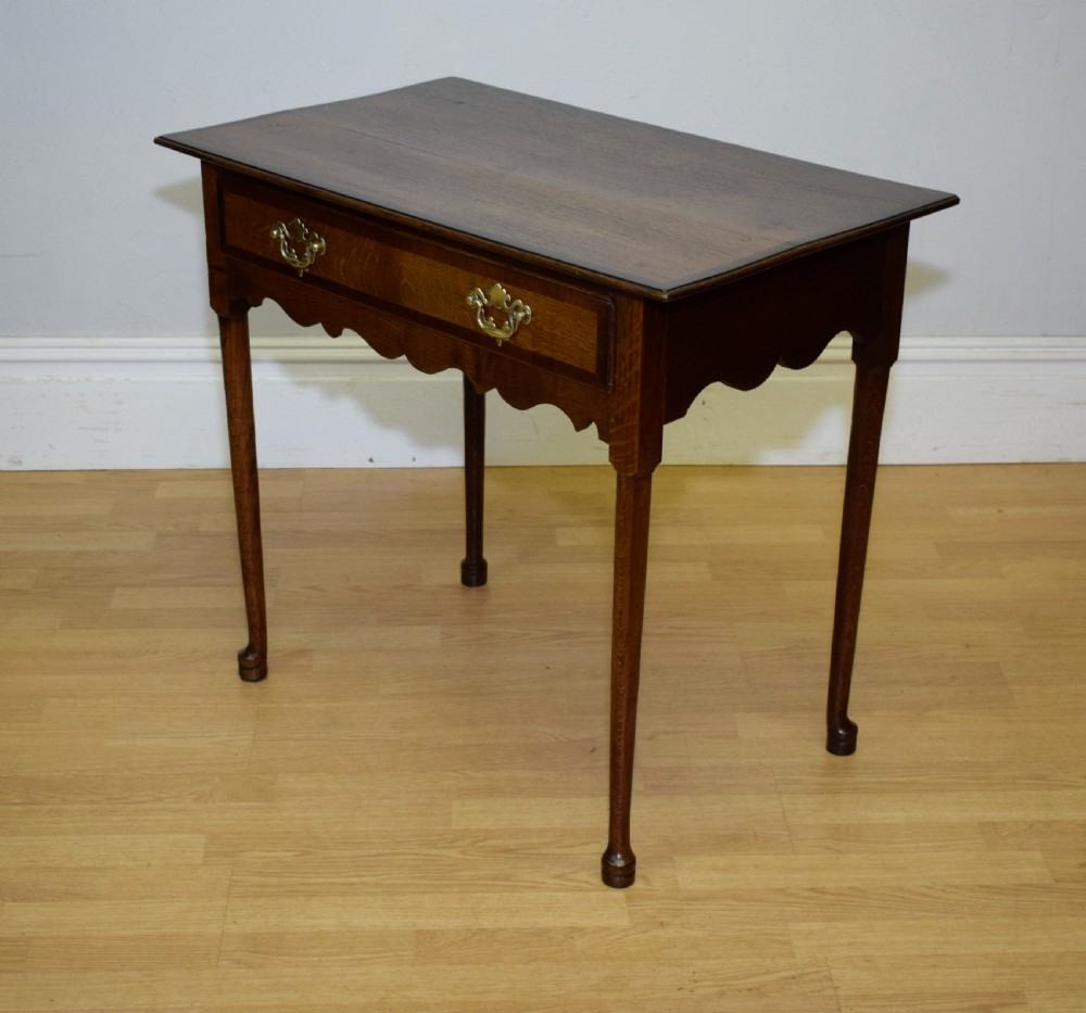 A Georgian oak lowboy side table featuring a single drawer with brass swan-neck handles and a scalloped lower apron. View IX