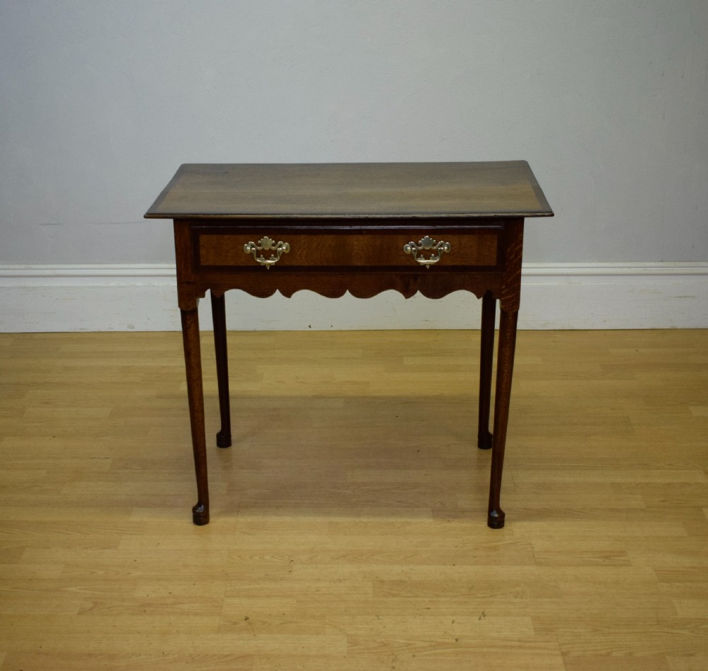A Georgian oak lowboy side table featuring a single drawer with brass swan-neck handles and a scalloped lower apron. View XIII