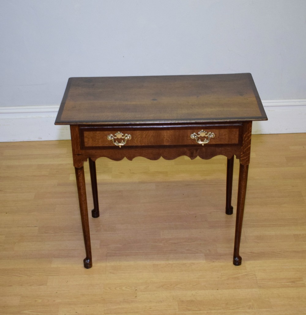 A Georgian oak lowboy side table featuring a single drawer with brass swan-neck handles and a scalloped lower apron. View XIV