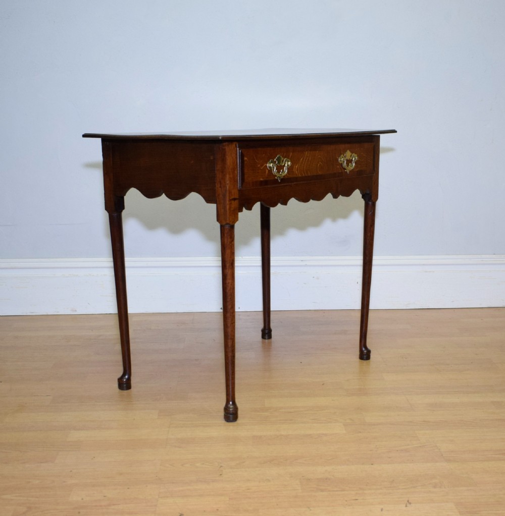 A Georgian oak lowboy side table featuring a single drawer with brass swan-neck handles and a scalloped lower apron. View XVI