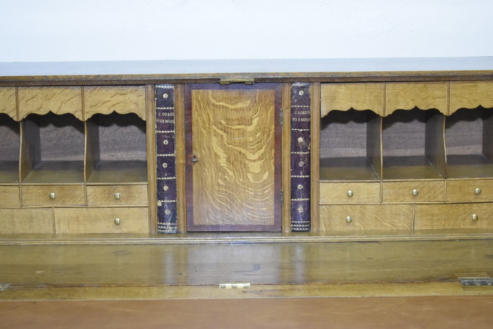 A Georgian oak bureau featuring a slanted fall-front lid above four graduated drawers fitted with brass oval handles and raised on bracket feet. View VII