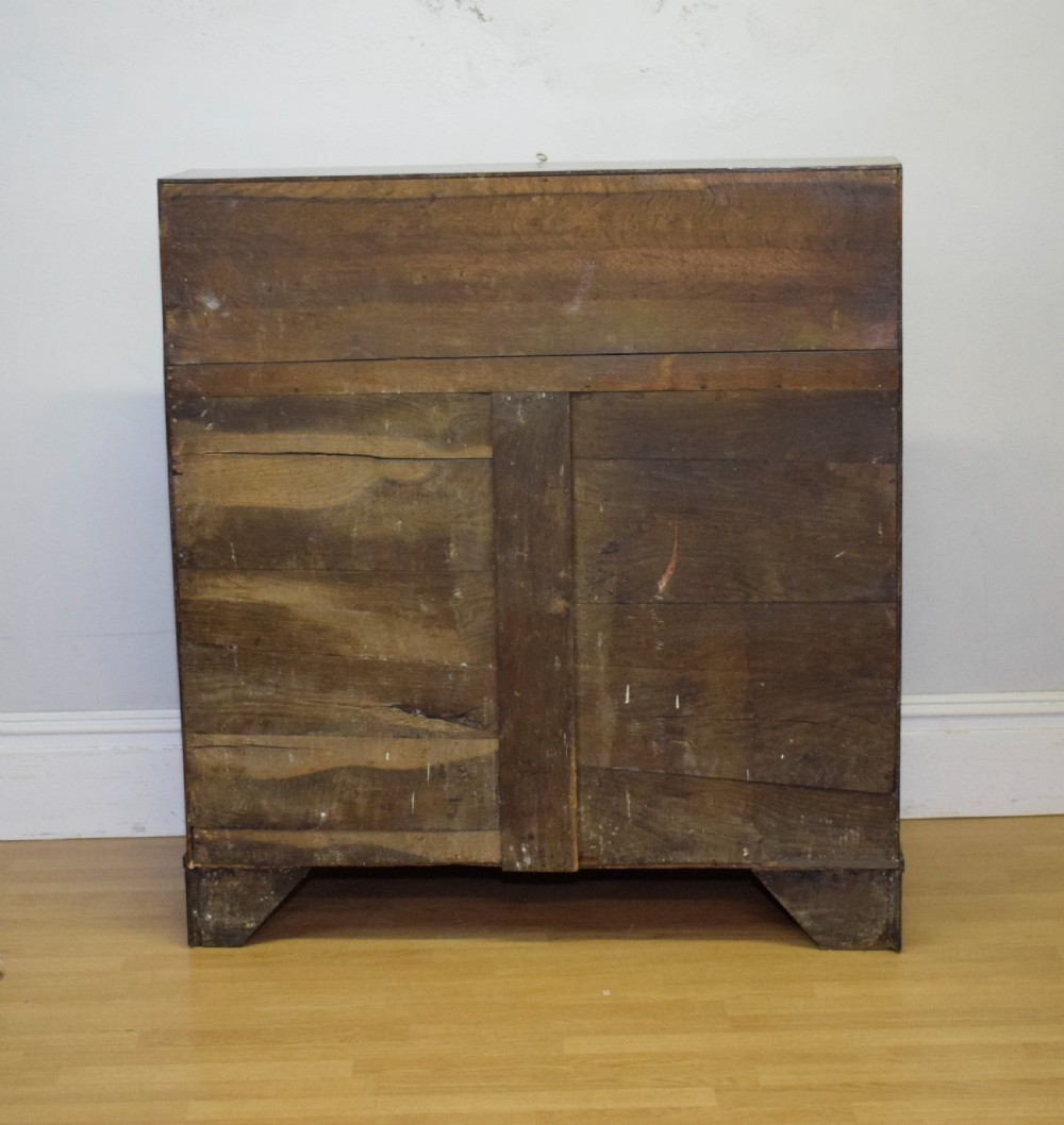 A Georgian oak bureau featuring a slanted fall-front lid above four graduated drawers fitted with brass oval handles and raised on bracket feet. View XXVIII