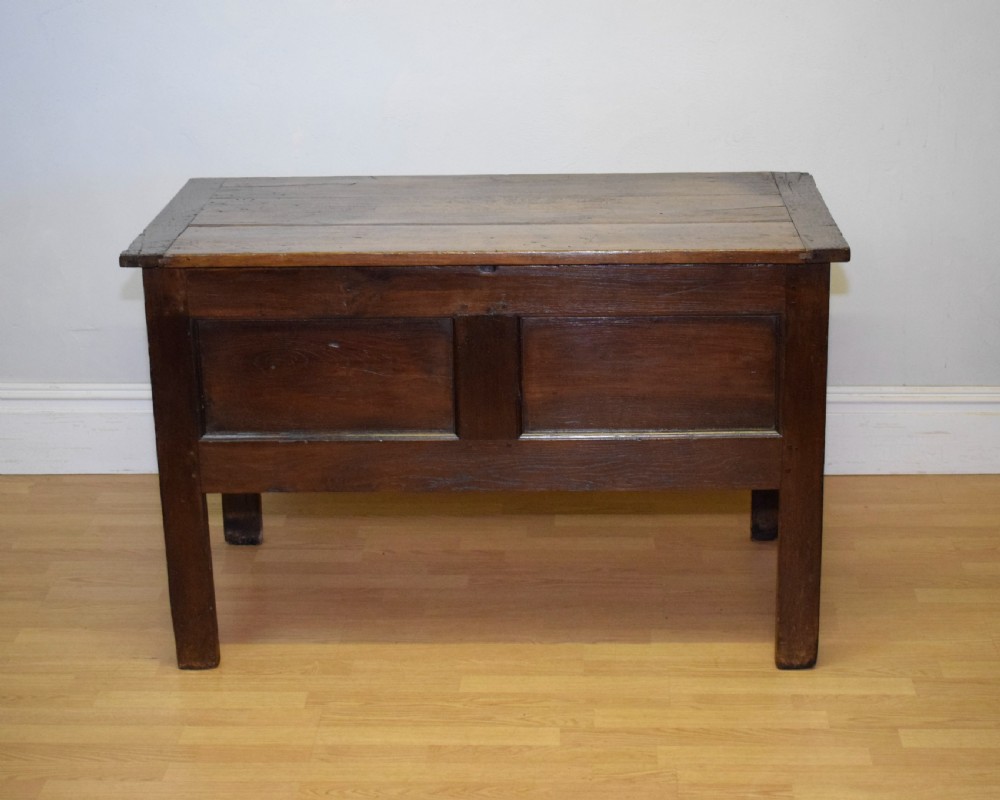 A dark oak seventeenth-century coffer featuring two plain rectangular front panels and a flat hinged top.