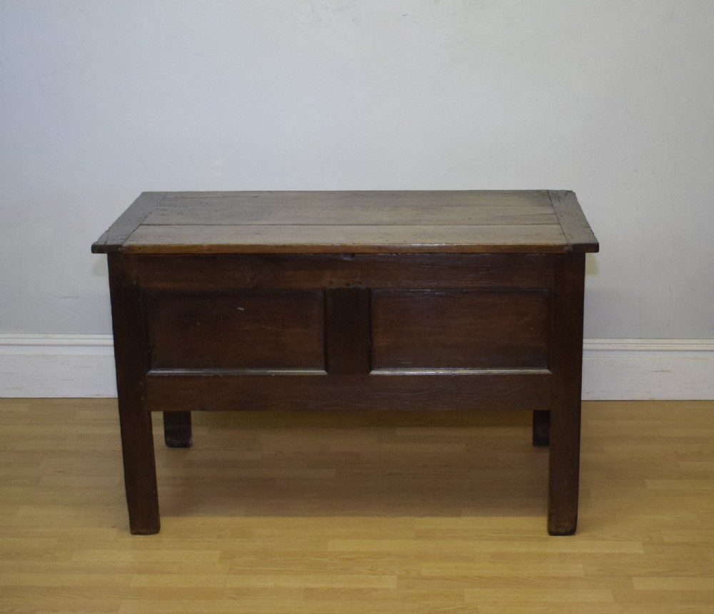 A dark oak seventeenth-century coffer featuring two plain rectangular front panels and a flat hinged top. View II