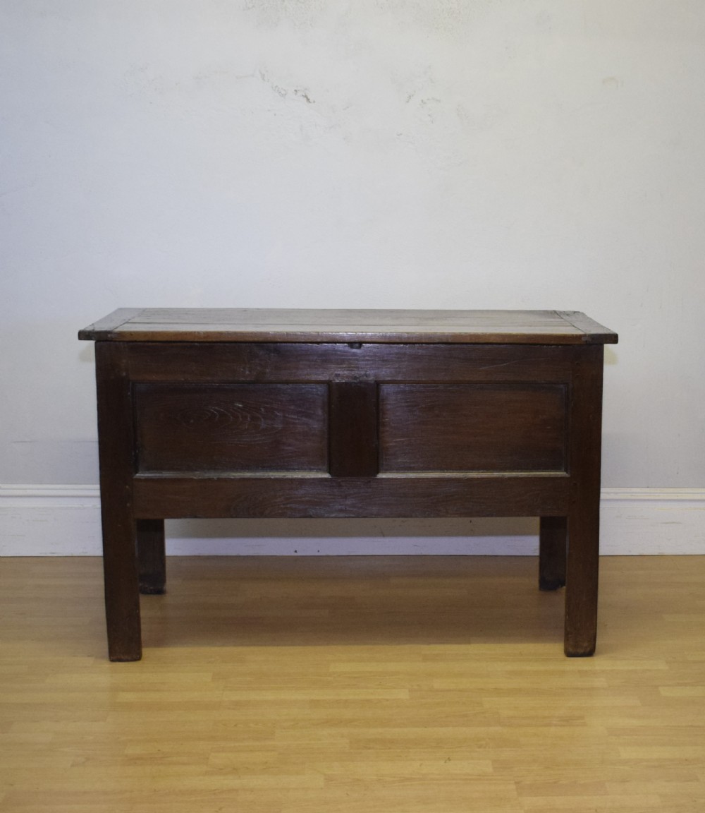 A dark oak seventeenth-century coffer featuring two plain rectangular front panels and a flat hinged top. View V