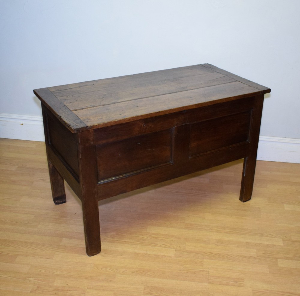 A dark oak seventeenth-century coffer featuring two plain rectangular front panels and a flat hinged top. View XII
