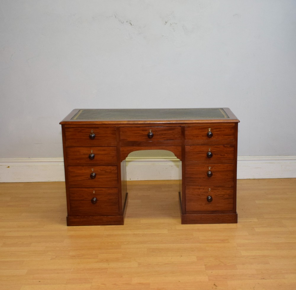 A Victorian mahogany pedestal desk with nine drawers, turned wooden handles, a dark leather insert top, and a central kneehole. View II