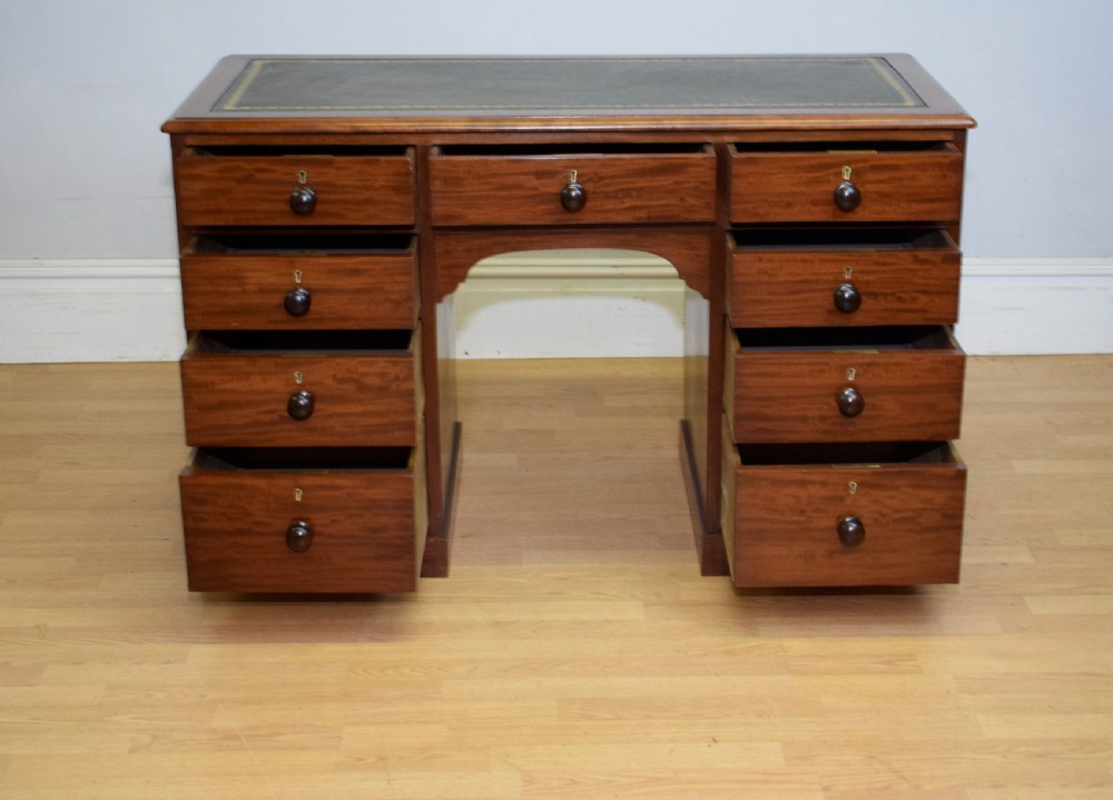 A Victorian mahogany pedestal desk with nine drawers, turned wooden handles, a dark leather insert top, and a central kneehole. View V