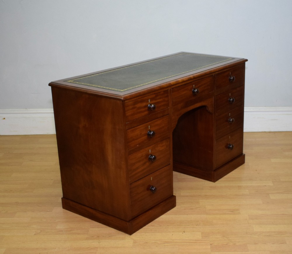 A Victorian mahogany pedestal desk with nine drawers, turned wooden handles, a dark leather insert top, and a central kneehole. View VII