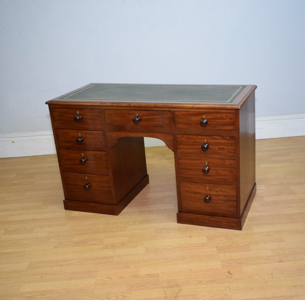 A Victorian mahogany pedestal desk with nine drawers, turned wooden handles, a dark leather insert top, and a central kneehole. View VIII