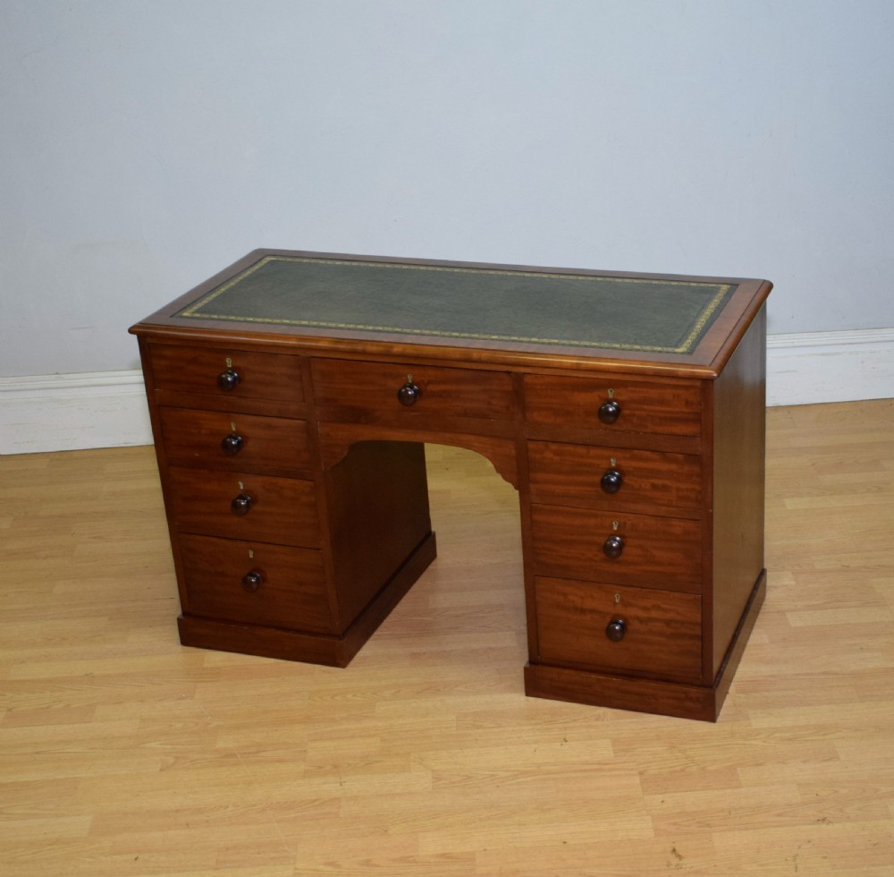 A Victorian mahogany pedestal desk with nine drawers, turned wooden handles, a dark leather insert top, and a central kneehole. View IX