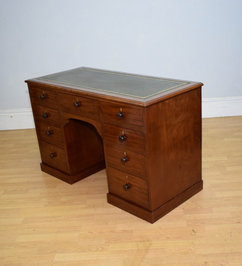 A Victorian mahogany pedestal desk with nine drawers, turned wooden handles, a dark leather insert top, and a central kneehole. View X