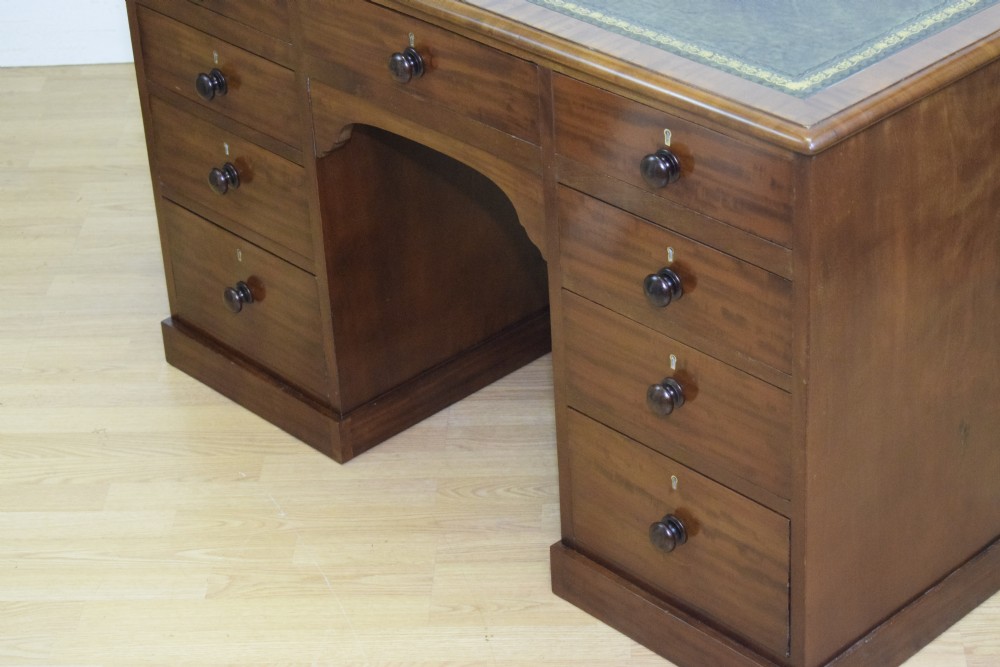 A Victorian mahogany pedestal desk with nine drawers, turned wooden handles, a dark leather insert top, and a central kneehole. View XI