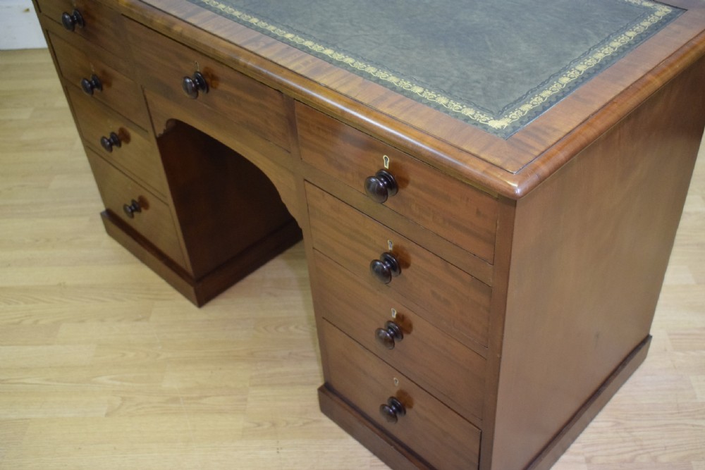A Victorian mahogany pedestal desk with nine drawers, turned wooden handles, a dark leather insert top, and a central kneehole. View XIV