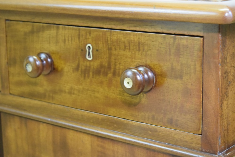 A Victorian mahogany pedestal desk featuring a dark green leather inset writing surface, three frieze drawers, and arched panel pedestal doors. View XX