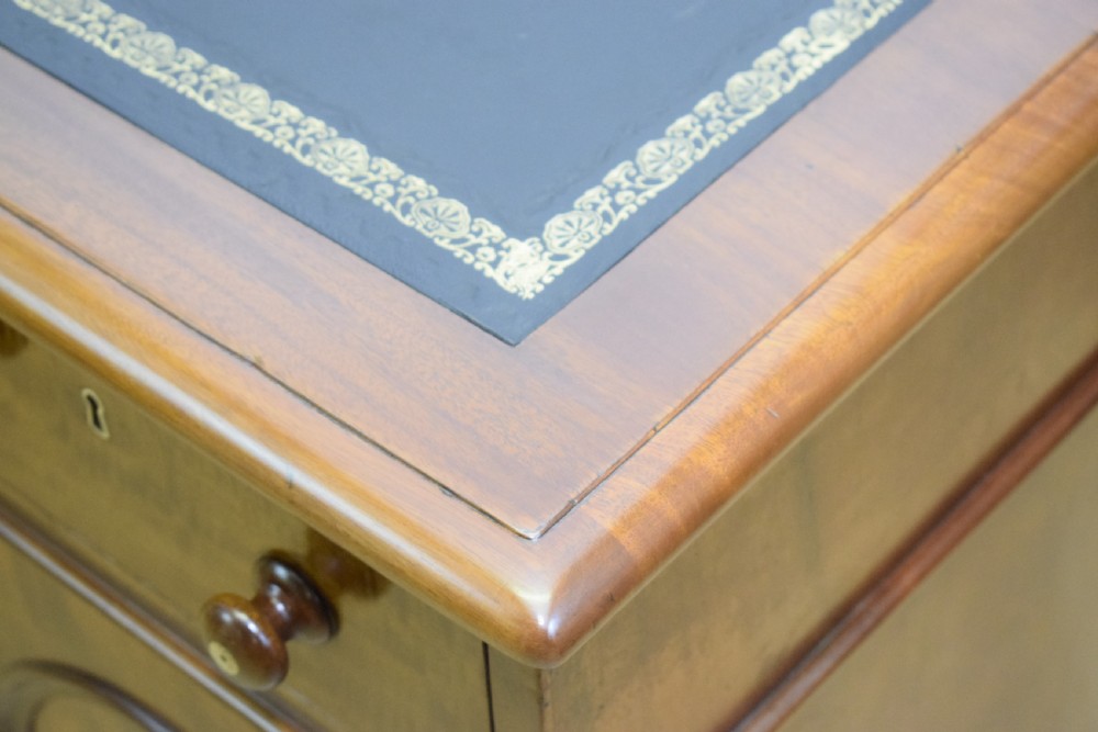 A Victorian mahogany pedestal desk featuring a dark green leather inset writing surface, three frieze drawers, and arched panel pedestal doors. View XXI